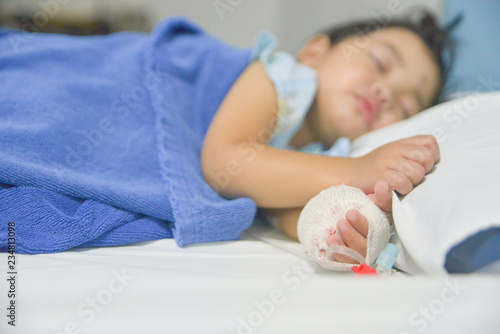 Asian little child's patient hand with saline intravenous (iv) drip in the hospital.