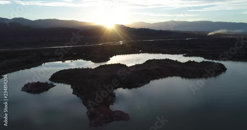 Aerial drone scene of lake and Desaguadero river surrounded of silhuetes of mountains at sunset, golden hour. Descending over water  beautiful reflections of clouds and sun over lake photo