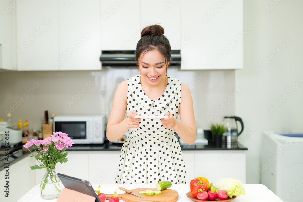 Young pretty woman using smart phone while cooking in kitchen Young pretty woman using smart phone while cooking in kitchen