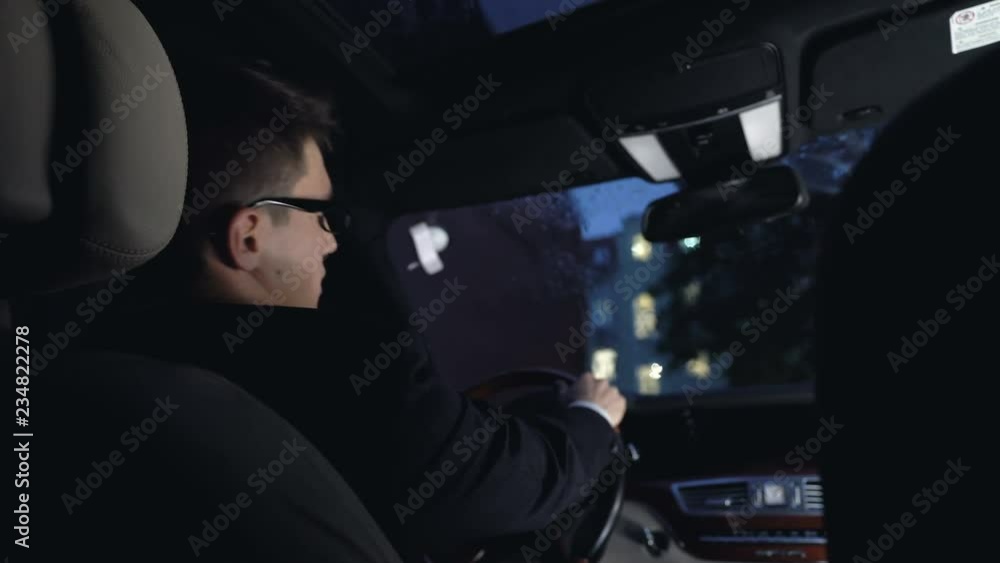 Thoughtful businessman sitting in car at nighttime, rainy weather, bad mood Thoughtful businessman sitting in car at nighttime, rainy weather, bad mood