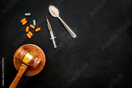 Drugs addiction, arrest for drugs. Pills, spoon with powder, syringe on black background top view copy space