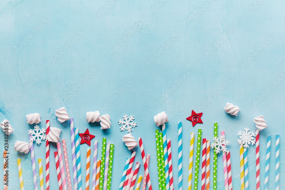 Drinking paper colorful straws for New Year cocktails on light blue background. Christmas card. Top view.