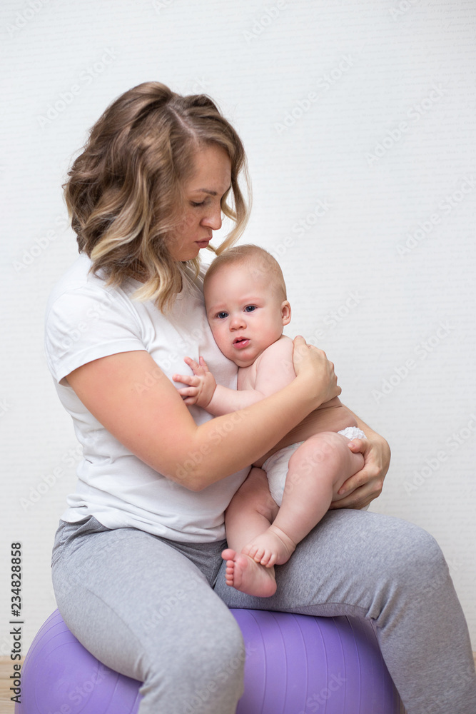 mother and her baby doing exercises on a ball