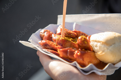 Frau  isst Currywurst unterwegs draußen am Wochenmarkt Imbiss photo
