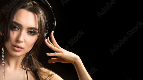 close up portrait of a woman, who listening to the music in headphones on dark background