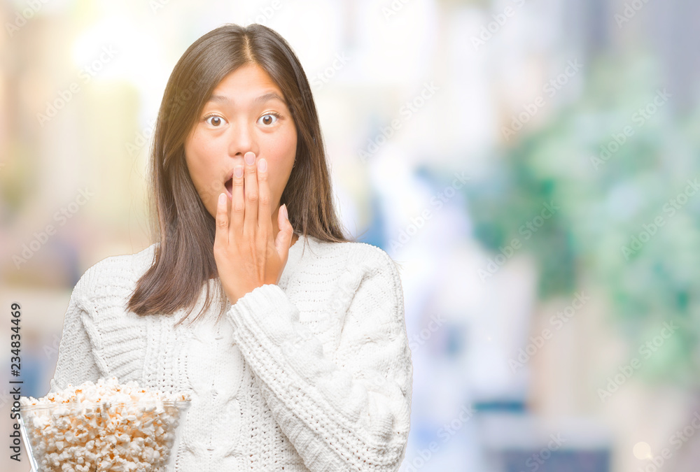 Young asian woman eating popcorn over isolated background cover mouth with hand shocked with shame for mistake, expression of fear, scared in silence, secret concept Young asian woman eating popcorn over isolated background cover mouth with hand shocked with shame for mistake, expression of fear, scared in silence, secret concept