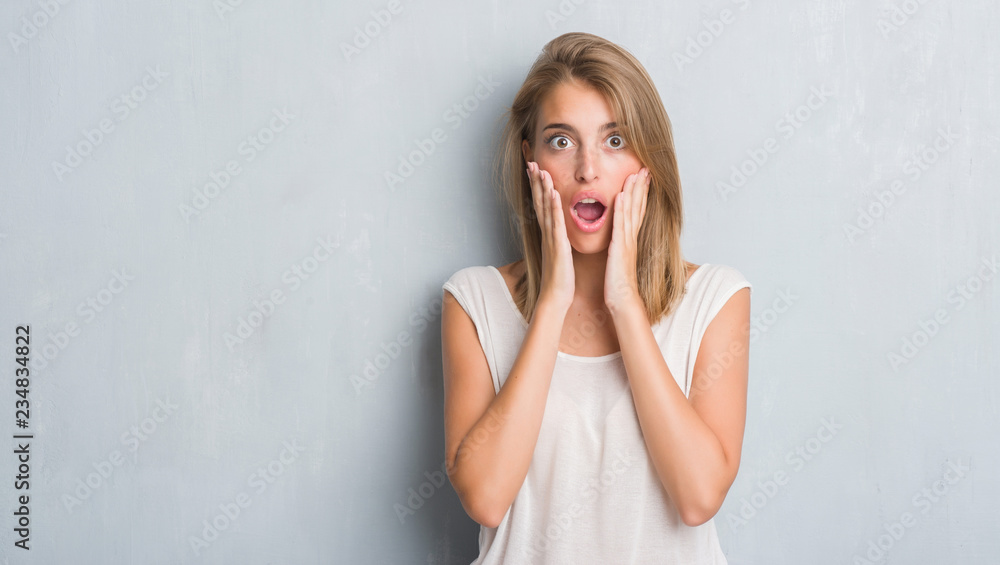 Beautiful young woman standing over grunge grey wall scared in shock with a surprise face, afraid and excited with fear expression Beautiful young woman standing over grunge grey wall scared in shock with a surprise face, afraid and excited with fear expression