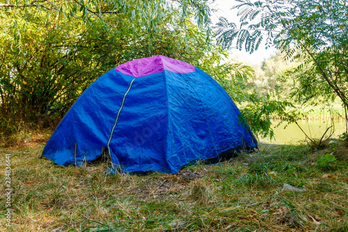 Blue camping tent in forest near a river