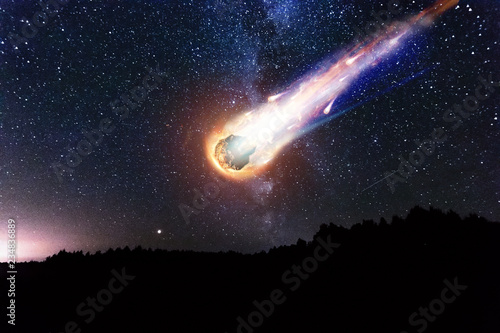 A comet, an asteroid, a meteorite falls to the ground against a starry sky. Attack of the meteorite. Meteor Rain. Kameta tail. End of the world. Astranomy. photo