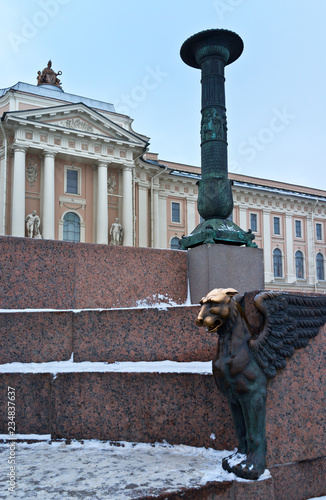 St. Petersburg. View from the granite embankment of the Neva River on the building of the Academy of Arts on Vasilyevsky Island in winter. Mythical old winged griffin (1834) - tourist attraction