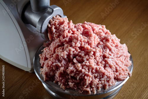 Minced meat coming out from modern electric grinder on oak table. Healthy fresh homemade minced meat. Place for copyspace
