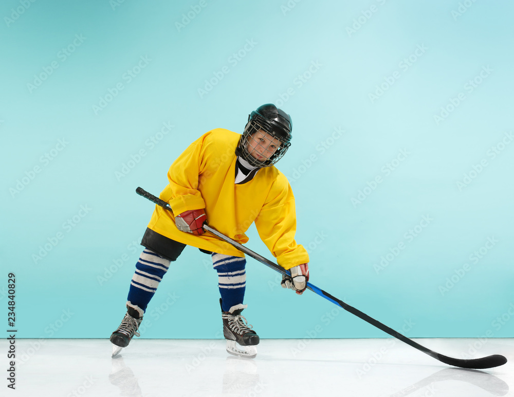 Obraz premium A hockey player in uniform with equipment over a blue studio background. The athlete, child, sport, action concept