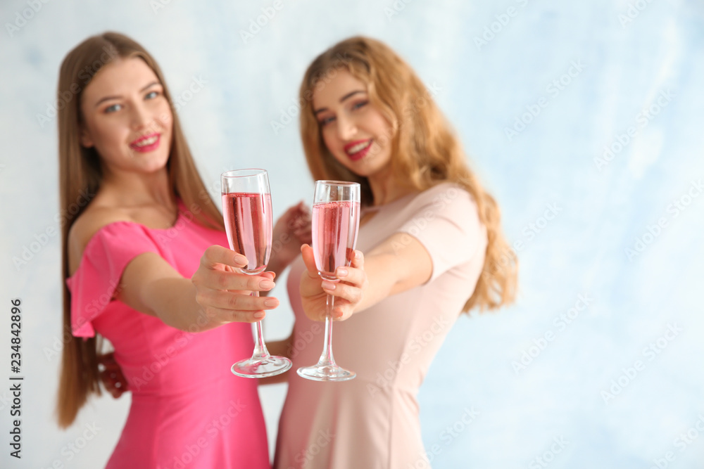 Beautiful young women with glasses of champagne on light background Beautiful young women with glasses of champagne on light background