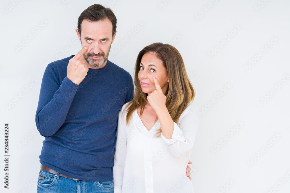 Beautiful middle age couple in love over isolated background Pointing to the eye watching you gesture, suspicious expression Beautiful middle age couple in love over isolated background Pointing to the eye watching you gesture, suspicious expression