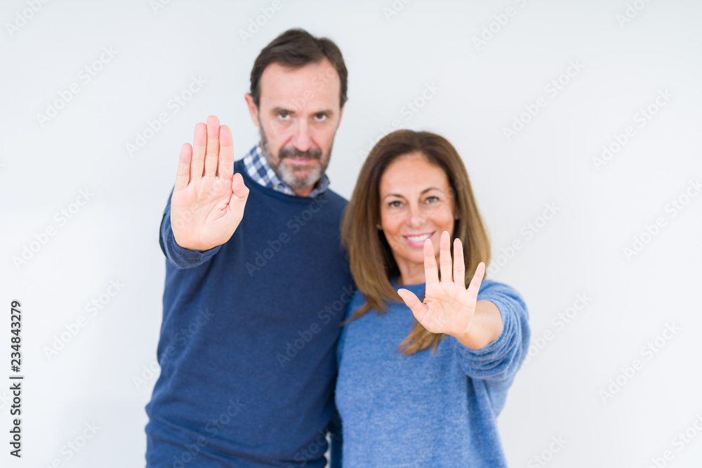 Beautiful middle age couple in love over isolated background doing stop sing with palm of the hand. Warning expression with negative and serious gesture on the face. Beautiful middle age couple in love over isolated background doing stop sing with palm of the hand. Warning expression with negative and serious gesture on the face.