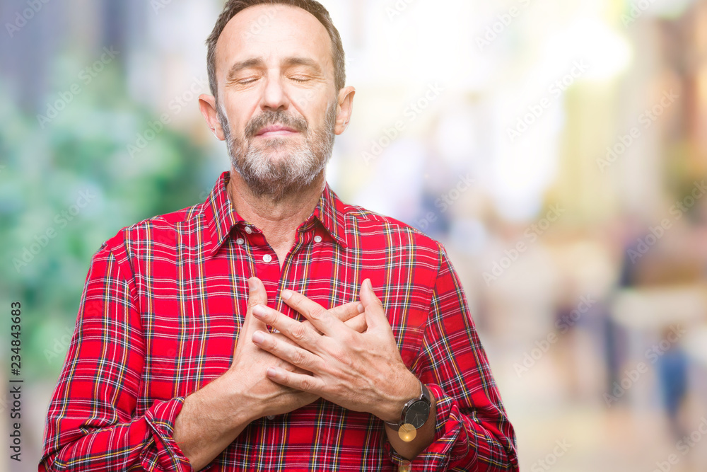 Obraz premium Middle age hoary senior man over isolated background smiling with hands on chest with closed eyes and grateful gesture on face. Health concept.
