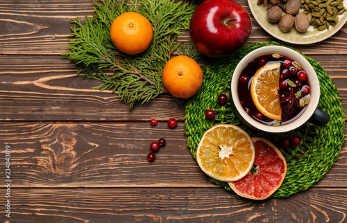 Cup of tasty mulled wine and ingredients on wooden background