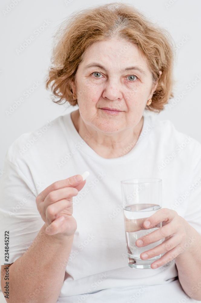 Senior woman holding pills and glass of water Senior woman holding pills and glass of water