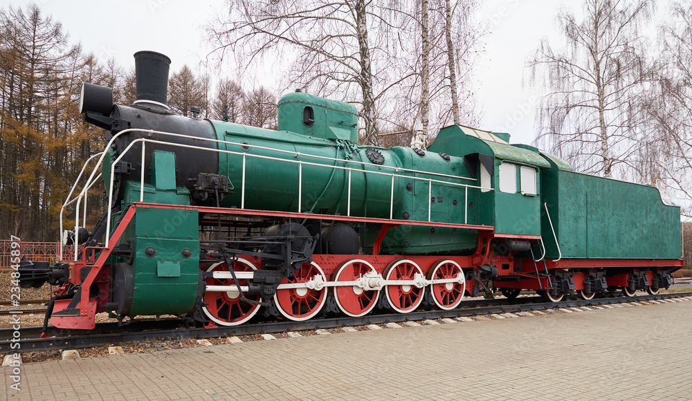 Obraz premium Side view of classic old green steam locomotive on rail tracks