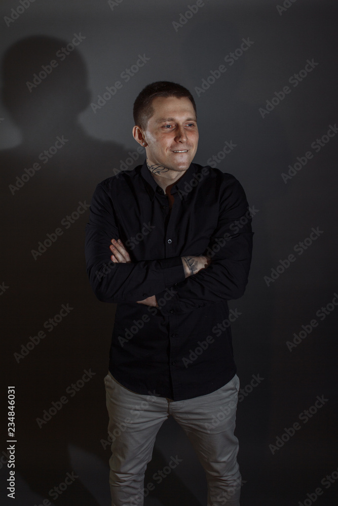Fototapeta premium Portrait of determined goodlooking man wearing black shirt, black background.