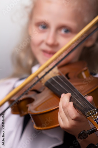 Smiling little girl in elegant clothes playing the violin