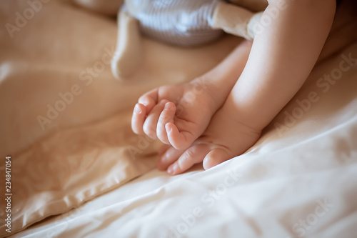 The baby is sleeping on the bed. Child's hand close up.