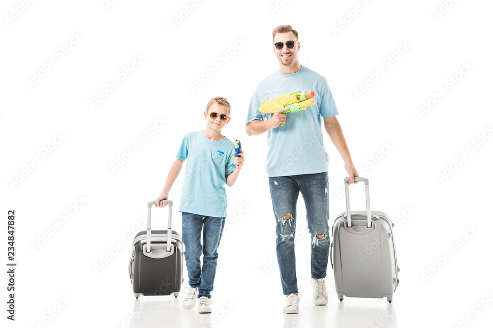 Dad and son walking with luggage and holding water guns isolated on white Dad and son walking with luggage and holding water guns isolated on white