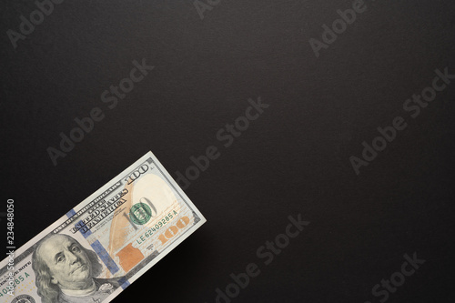 Hundred dollar bill in the corner of black background