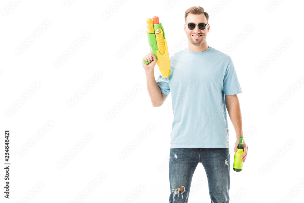 Smiling man standing in sunglasses with bottle and water gun isolated on white Smiling man standing in sunglasses with bottle and water gun isolated on white