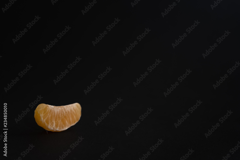 Tangerine slice on a black background Tangerine slice on a black background