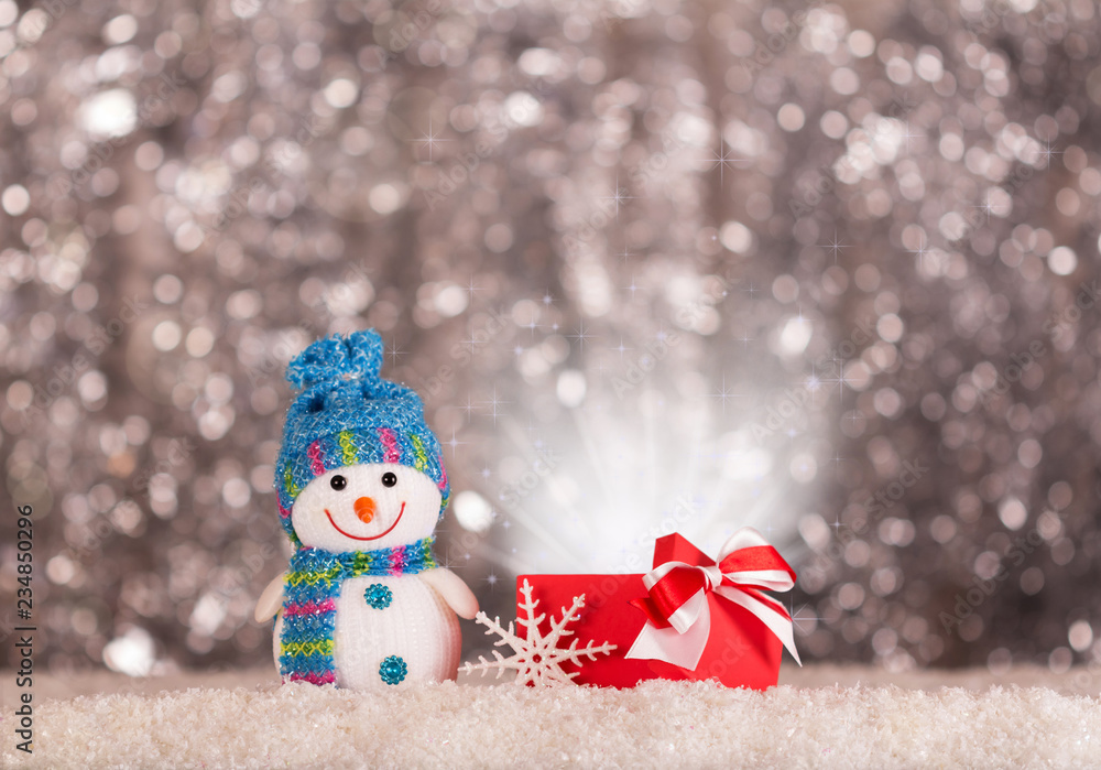 Smiling snowman and magical gift in the snow on bright grey background