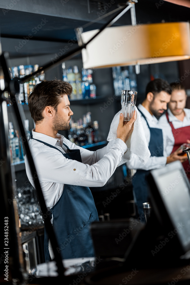 handsome barman looking at clean glass at workplace handsome barman looking at clean glass at workplace