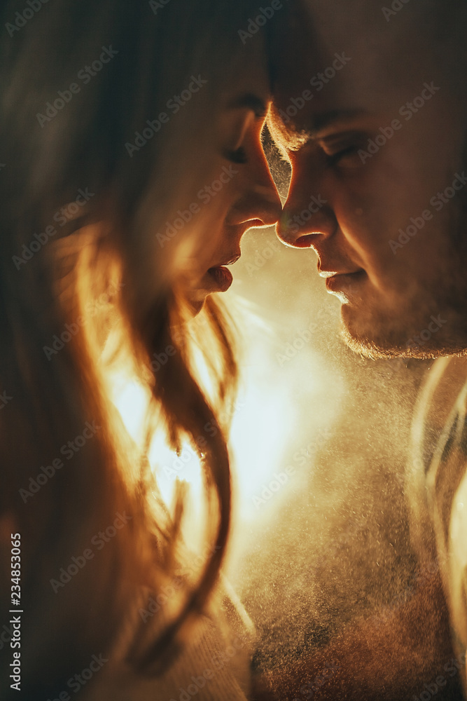 Obraz premium Portrait of the young couple in love standing face to face against the light of the lamp.