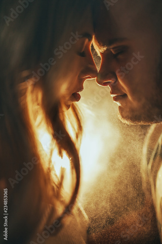Принти на полотні Portrait of the young couple in love standing face to face against the light of the lamp