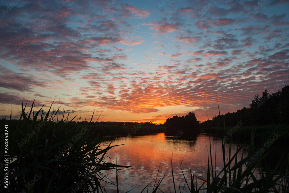 Beautiful orange colored altocumulus clouds near a small lake in Waddinxveen, The Netherlands at sunset