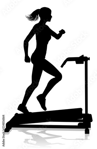 A woman in silhouette using a treadmill running machine piece of gym fitness equipment 