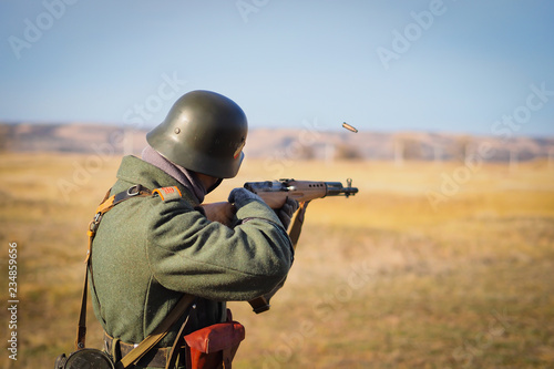 Soldier shoots a rifle on the battlefield, rear view