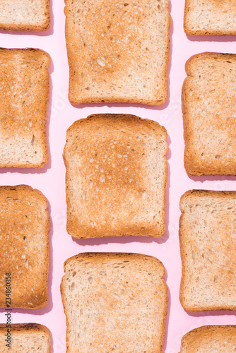 top view of pattern of crispy toasts on pink surface