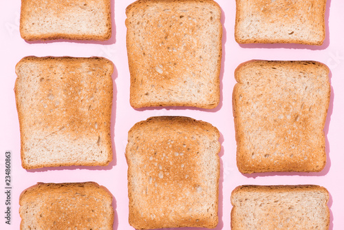 top view of repetitive pattern of crispy toasts on pink surface