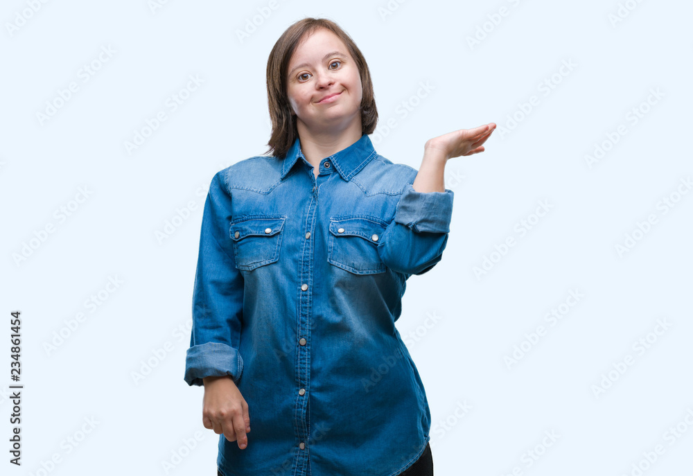 Young adult woman with down syndrome over isolated background smiling cheerful presenting and pointing with palm of hand looking at the camera. Young adult woman with down syndrome over isolated background smiling cheerful presenting and pointing with palm of hand looking at the camera.