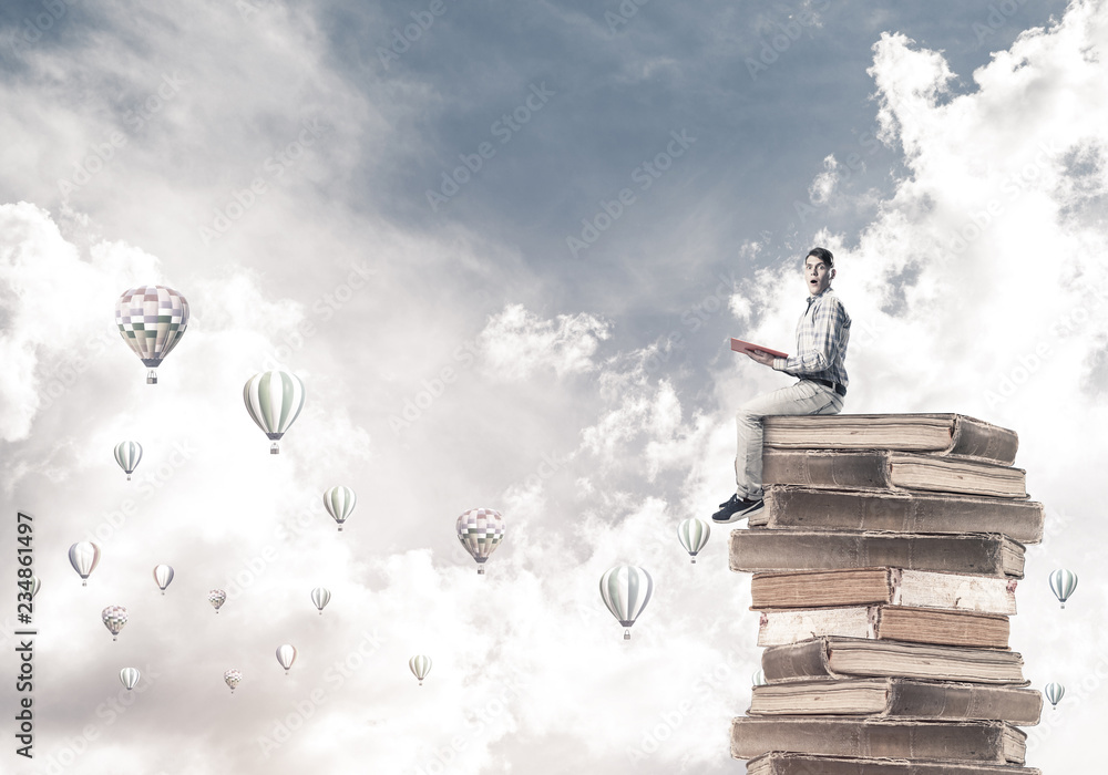 Man student on stack reading book and aerostats flying around Man student on stack reading book and aerostats flying around