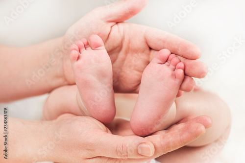 Mother doctor massage therapist doing heel massage for a happy child, applies oil on her leg, on a white background