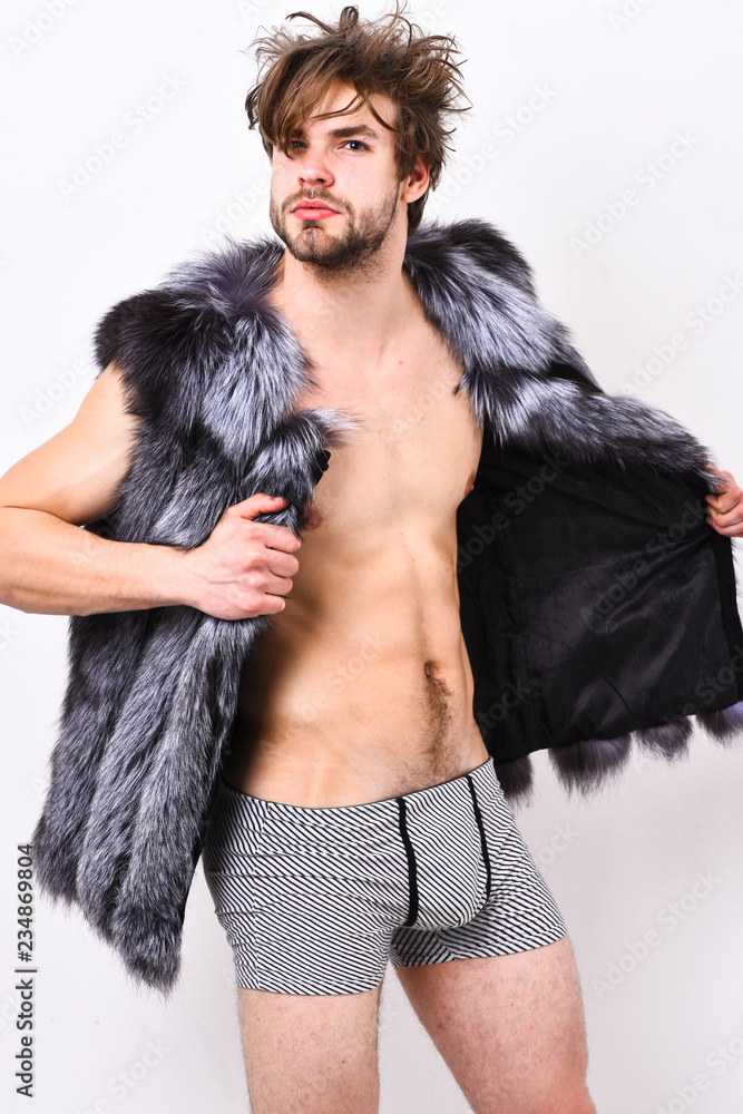 Fashion concept. Richness and luxury lifestyle. Sexy sleepy rich macho  tousled hair fur vest on white background. Guy attractive fashion model  posing fur coat on naked body. Fashion and pathos Stock Photo