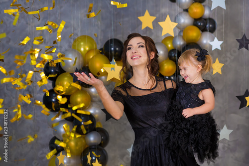 Woman power party with model mother and cute baby daughter dressed in airy black fancy dresses celebrating love with golden stars air baloons. Pillow stars SUPER STAR designed by photographer.