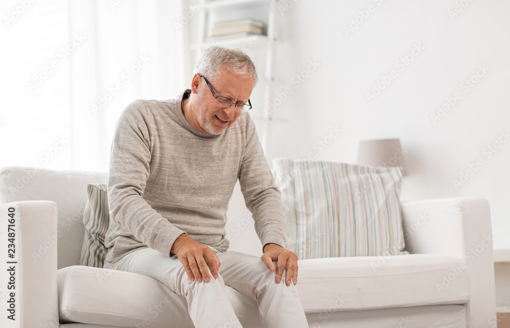 people, health care and problem concept - unhappy senior man suffering from knee ache at home