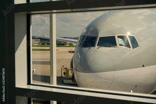 Airplane standing behind a window glass at the airport gate, waiting for passengers to board.
