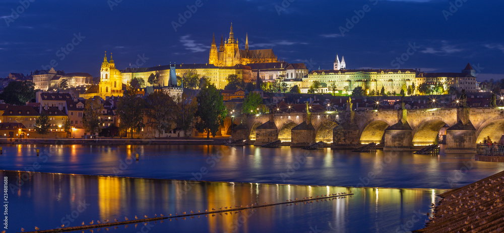 Prague - The Charles Bridge, Castle and Cathedral from promenade over the  Vltava river at dusk.