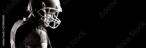 Photography American football player in helmet standing against black
