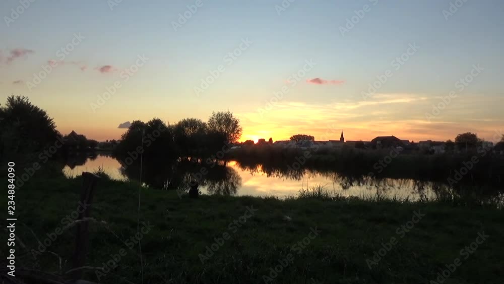 Sun Setting on Lake with Dutch Landscape and Church in background Sun Setting on Lake with Dutch Landscape and Church in background