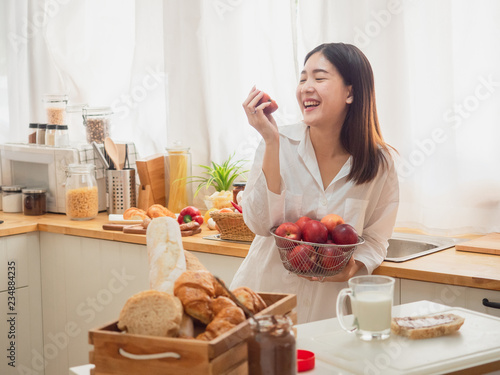 asian woman eating fruit in the kitchen